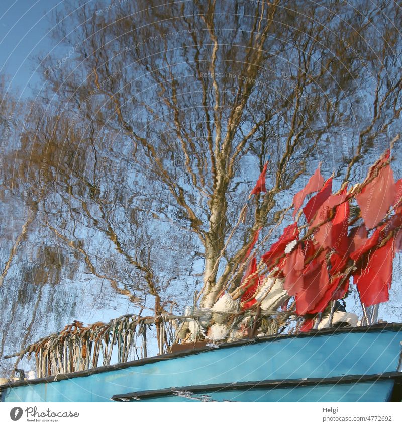Spiegelung eines Fischerbootes mit roten Fähnchen und Haken, im Hintergrund ein Baum vor blauem Himmel Wasser Detailaufnahme Reflexion & Spiegelung