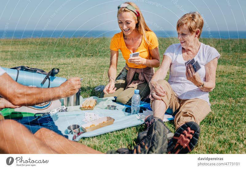 Junge Frau und ältere Frau spielen Karten in der Familie während eines Ausflugs Senior jung Frauen Postkarte zu feiern Lächeln Schüreisen Glück Spaß im Freien