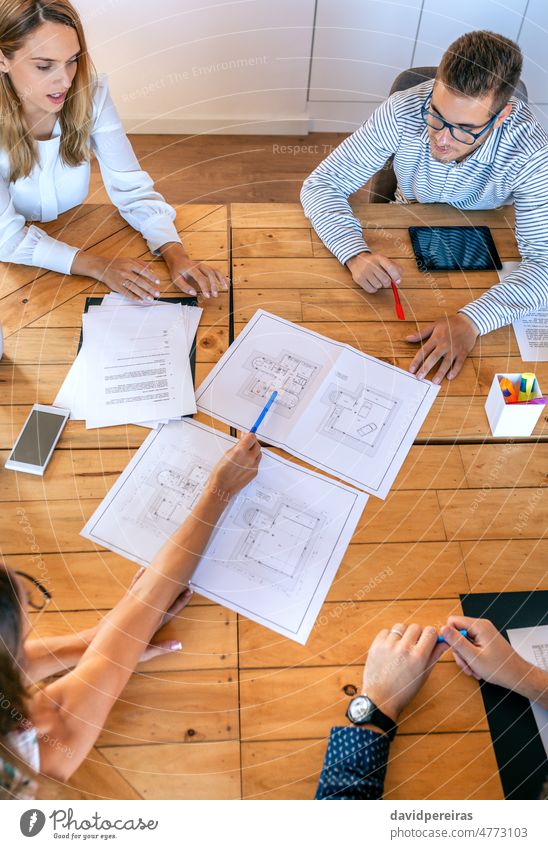 Draufsicht auf Architekten bei einer Arbeitssitzung mit Blick auf Konstruktionszeichnungen Teamwork Geschäftsleute Büro Arbeitstreffen Zusammenarbeit Zeigen