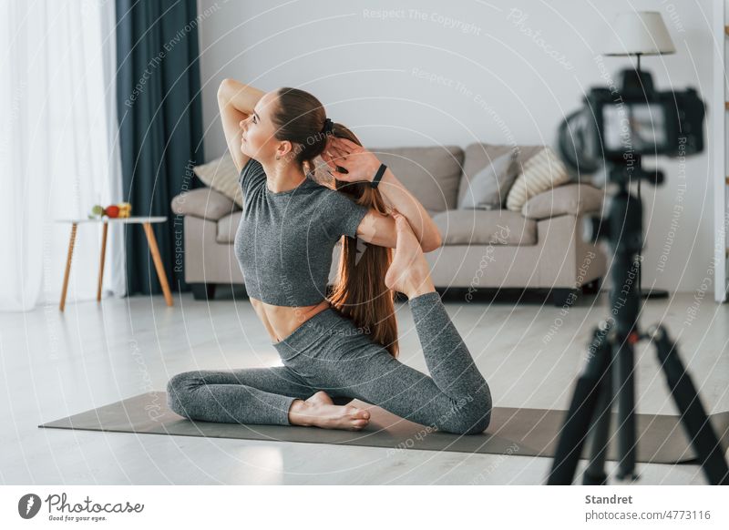 Unterricht vor der Kamera. Junge Frau mit schlanken Körper-Typ und in Yoga-Kleidung ist zu Hause Fitness Gesundheit Lifestyle Fotokamera fotografisch Gerät