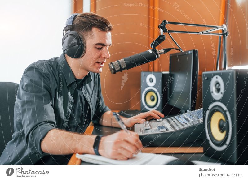 Spricht und benutzt Mikrofon. Junger Mann ist drinnen im Radiostudio mit der Übertragung beschäftigt Podcast Interview zeigen Atelier Wirt Präsentator live