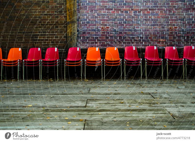 Alle Stühle zur Seite gestellt Reihe Sitzgelegenheit Bestuhlung Platz Menschenleer Stuhlreihe Sitzreihe Backsteinwand Podest Holzbrett Plastikstuhl viele