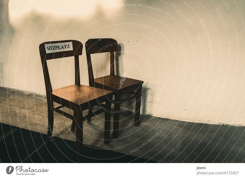 Dies ist nur ein Sitzplatz Sitzplätze 2 Stühle nebeneinander Kennzeichnung Sitzgelegenheit frei Reihe Abstand Kirche Menschenleer Wort geschrieben