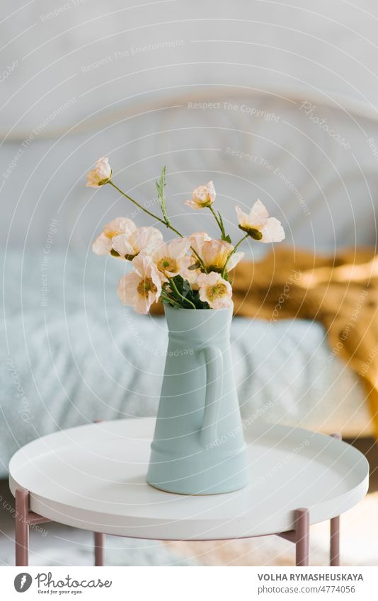 Künstliche Mohnblumen in einer blauen Vase in Form eines Kruges auf dem Couchtisch im Inneren des Raumes Blume altehrwürdig geblümt Natur Hintergrund weiß