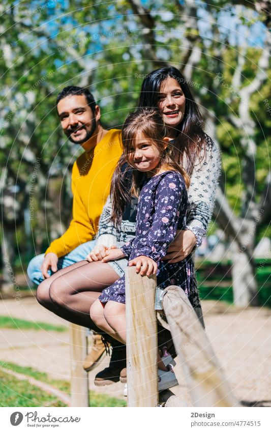 Glückliche Familie steht im grünen Park, während das kleine Mädchen in die Kamera schaut Zuneigung tragen Kinder Vater Schulter Zusammensein