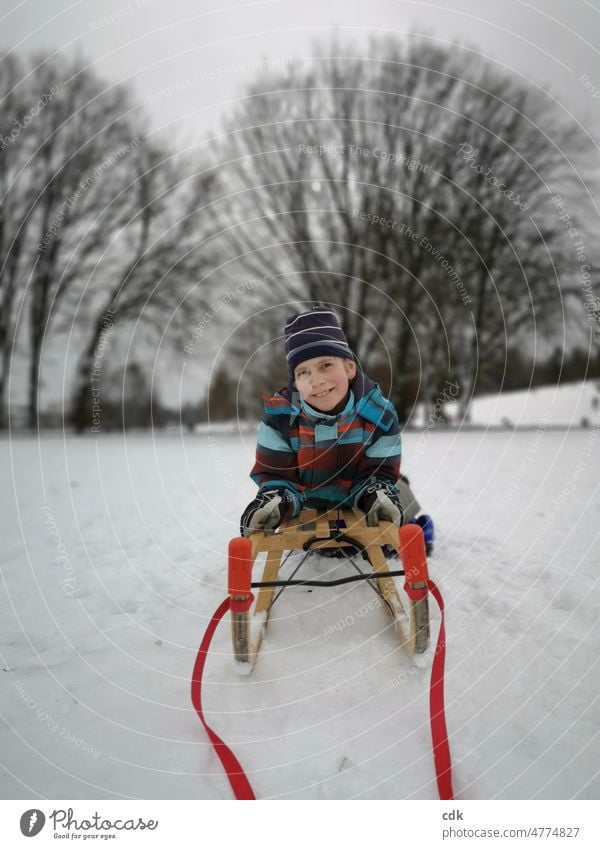Kindheit | vergnügter Junge mit Schlitten im Schnee. Mensch Winter Park weiß kahle Bäume rote Schlittenbänder weiße Landschaft Schlittenfahren Winterspaß