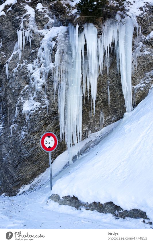Rekordverdächtig, gigantische Eiszapfen an einer Felswand, davor ein Verkehrsschild mit Höhenbegrenzung Frost Schnee Höhenangabe Winter gefroren kalt lustig