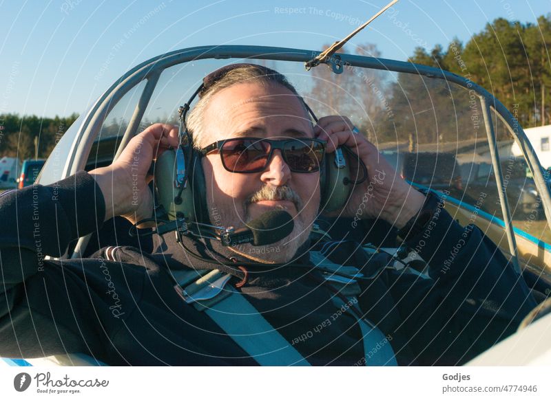 Portrait eines Mannes, der sich im Flugzeug ein Headset aufsetzt Fliegerei Bart Gesicht Porträt Erwachsene Mensch Brille Kopf Farbfoto Sonnenbrille maskulin
