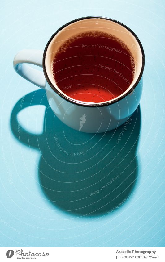 Eine Tasse schwarzer Tee auf blauem Hintergrund unter dem hellen Sonnenlicht. Getränk Frühstück braun Koffein ceylon China abschließen Konzept konzeptionell