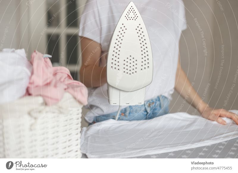 Frau hält modernes Bügeleisen mit Antihaftbeschichtung beim Bügeln Sohle bügelnd Belag erwärmen Verdunstung Wäscherei Hausarbeit Hausfrau heiß heimwärts
