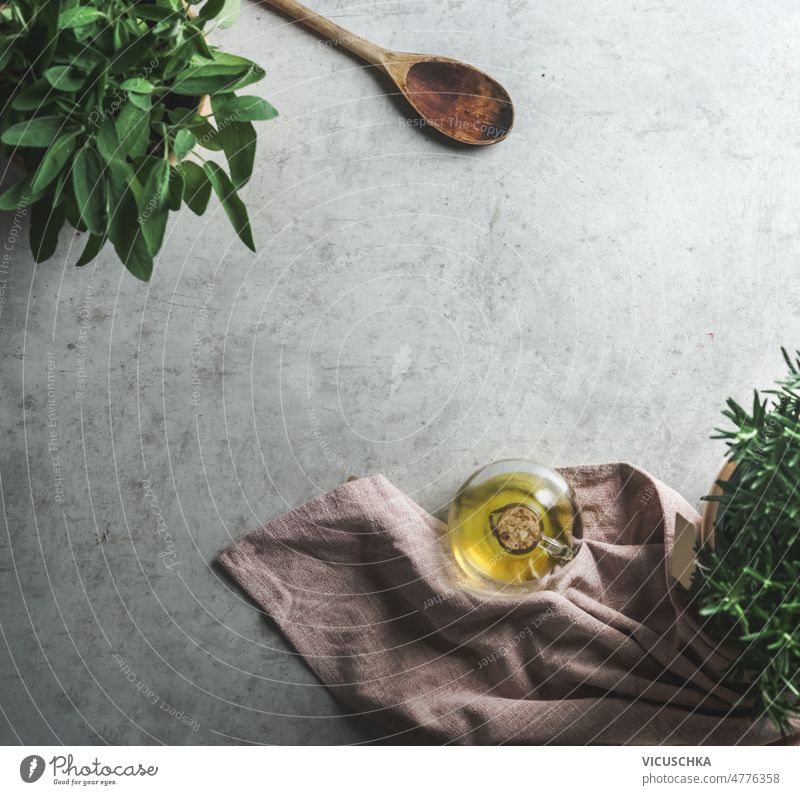 Lebensmittel Hintergrund mit Olivenöl, frische Kräuter und Kochlöffel Lebensmittelhintergrund Gesunde Inhaltsstoffe Flasche Salbei hölzern Löffel Rosmarin grau