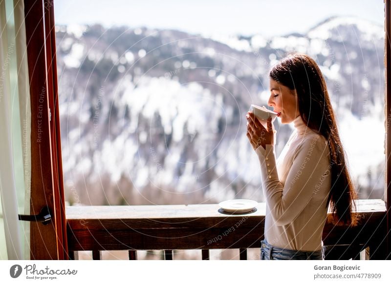 Junge Frau mit einer Tasse heißem Tee im Winterfenster Morgen Frühstück Lifestyle Fenster jung Leben sich[Akk] entspannen Menschen heimwärts Lächeln schön