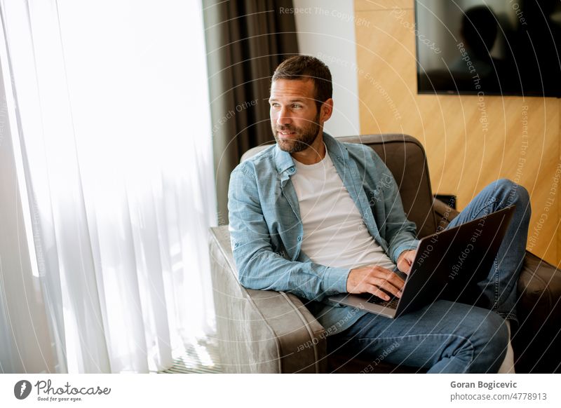 Junger Mann mit Laptop im Wohnzimmer Erwachsener Business Kaukasier Computer Elektronik Unternehmer Internet Job Lifestyle männlich modern Notizen Beruf Büro