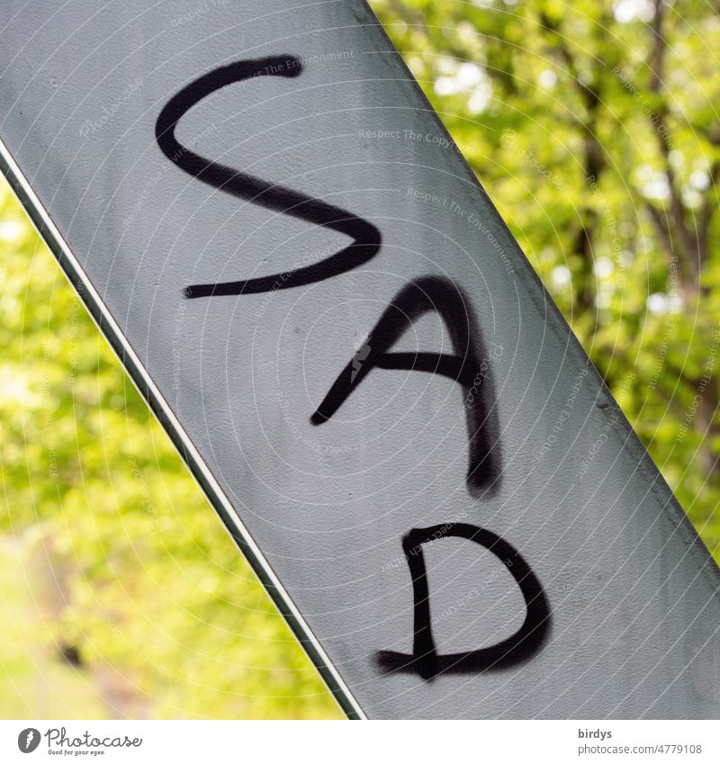 " Sad ", " traurig "  in englischer Schrift. Graffiti auf einer Metallstrebe. Formatfüllend, schwache Tiefenschärfe Traurigkeit Kummer Leid Sorge Schmerz