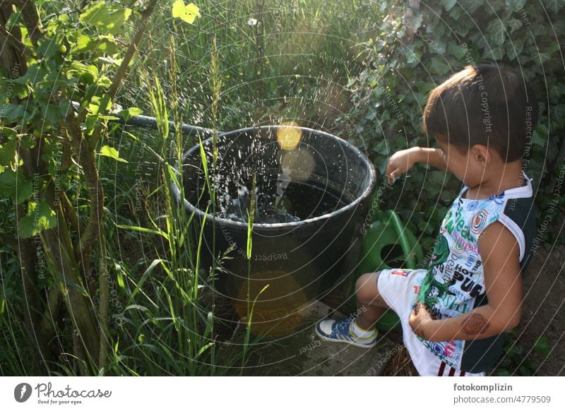 kleiner Junge spielt an einer Wassertonne im Garten Kind Kleinkind spielen Bottich Spielen Kindheit Freude Fröhlichkeit Außenaufnahme Spaß Sommer Lebensfreude