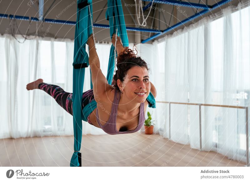 Fröhliche Frau in Schwan-Pose auf einer Schaukel pendeln Yoga Training üben Antenne Übung Gesunder Lebensstil Hängematte Asana Atelier Klasse geräumig Wellness