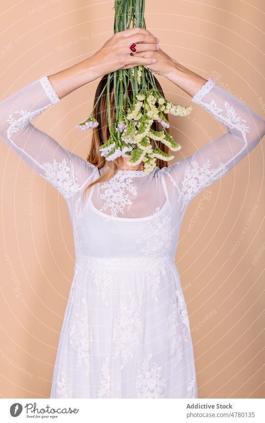 Anonyme Braut, die ihre Augen mit Blumen bedeckt Frau weißes Kleid Hochzeit Stil Anlass Blumenstrauß geblümt Augen abdecken Tierhaut Veranstaltung elegant