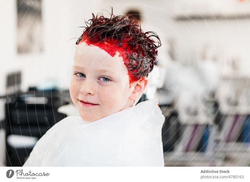 Junge mit rot gefärbtem Haar Kind Salon Kindheit rote Haare Porträt gefärbtes Haar auflehnen Vorschein Frisur informell Stil Klient trendy Licht bezaubernd