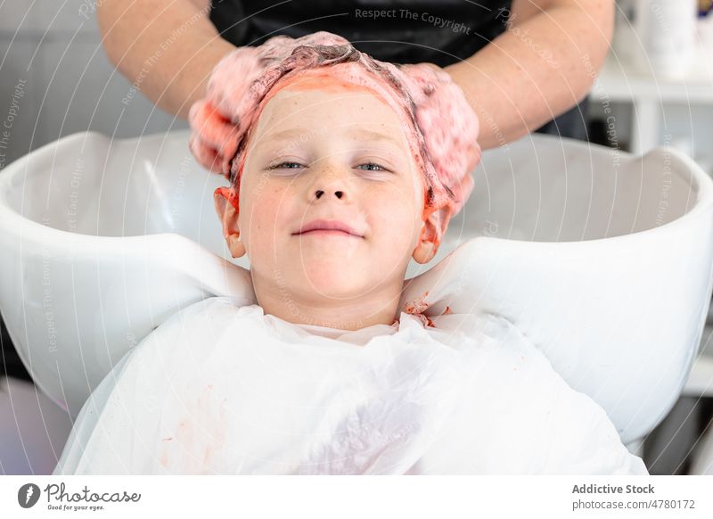 Unbekannter Meister wäscht dem Jungen die Haare Friseur Kind Salon rote Haare Haarwaschmittel gefärbtes Haar Waschen Wasser Waschbecken Frisur informell