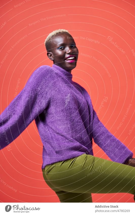 Optimistische afrikanische Frau mit Make-up Stil Kurze Haare gefärbtes Haar feminin trendy Mode Outfit Kleidung Kosmetik Kajal Vorschein Lächeln Afrikanisch