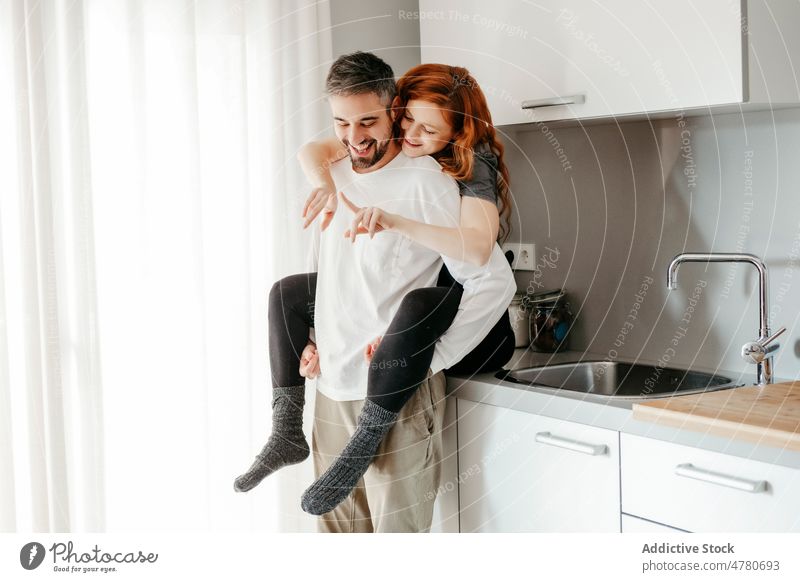 Verliebtes Paar, das sich in der Küche umarmt Partnerschaft Liebe Bonden kuscheln romantisch Zuneigung Rotschopf Huckepack Streicheln Umarmung Umarmen