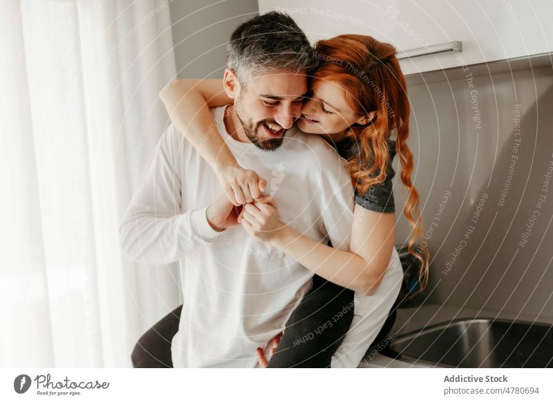 Verliebtes Paar, das sich in der Küche umarmt Partnerschaft Liebe Bonden kuscheln romantisch Zuneigung Huckepack Streicheln Umarmung Umarmen Rotschopf
