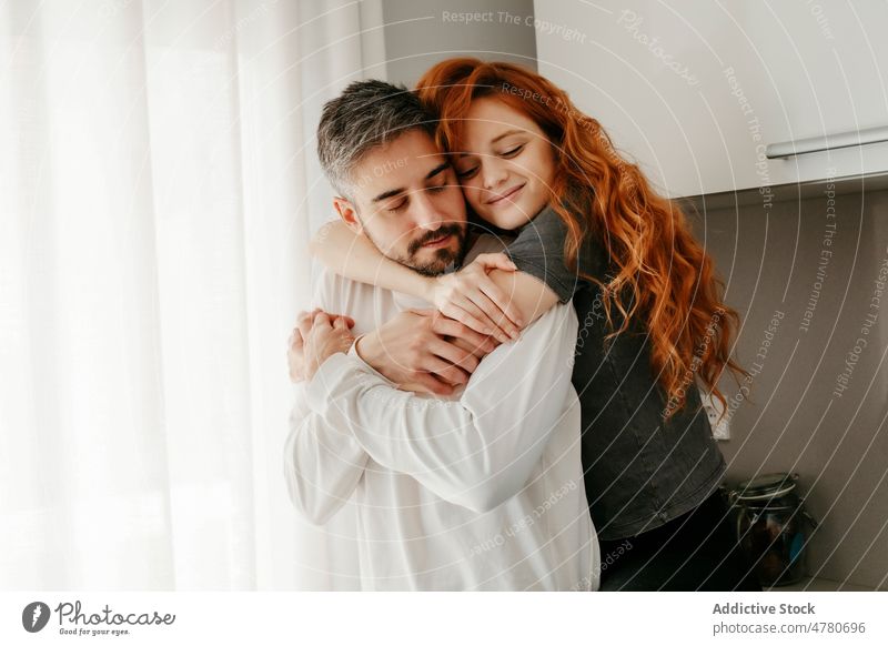 Verliebtes Paar, das sich in der Küche umarmt Partnerschaft Liebe Bonden kuscheln romantisch Zuneigung Rotschopf Streicheln Umarmung Umarmen Augen geschlossen