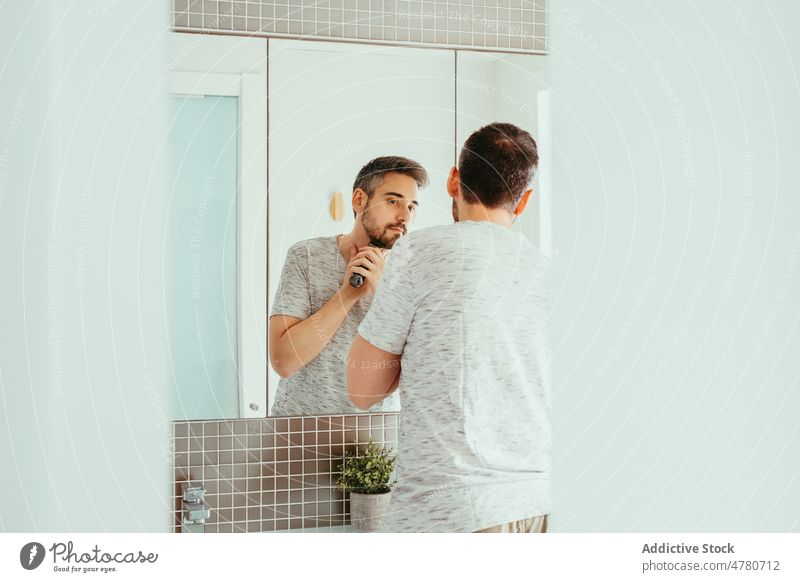 Mann rasiert Bart mit Trimmer Vollbart Rasieren Routine unrasiert Spiegel Hygiene täglich Bad Reflexion & Spiegelung heimwärts Vorschein männlich Licht Typ