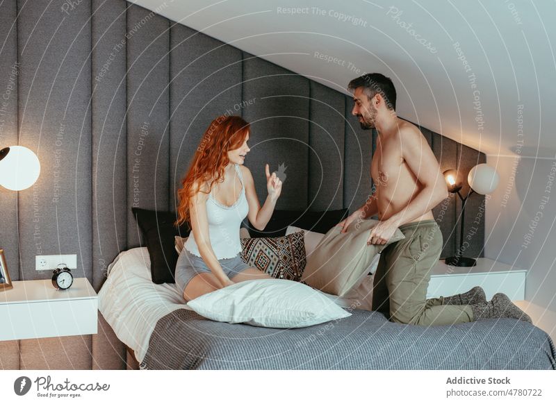 Fröhliches Paar kämpft mit Kissen auf dem Bett Schlafzimmer rote Haare Kissenschlacht Spaß haben sorgenfrei Partnerschaft Liebe Bonden spielerisch romantisch