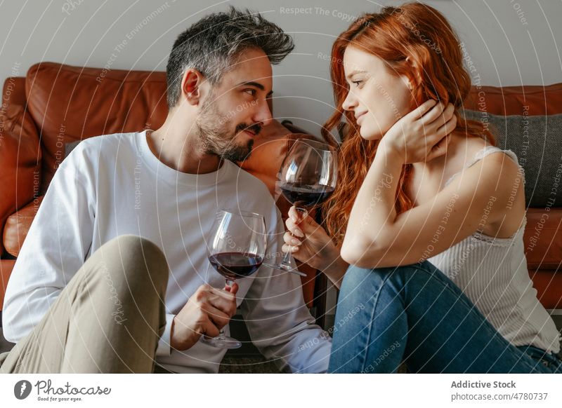 Verliebtes Paar mit Weingläsern auf dem Boden Partnerschaft Liebe Bonden romantisch Streicheln Weinglas Kuss feiern Zuneigung Rotschopf Ingwer Alkohol Schnaps