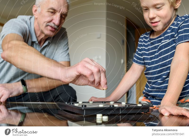 Großvater mit Enkel beim Damespiel Prüfer Spiel Familie Spielen Holzplatte Zusammensein Kind Senior Junge Person Strategie Spaß Freizeit Konkurrenz