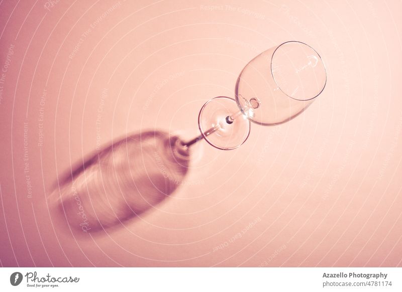 Leere Weinglas mit kreativen dunklen Schatten auf rosa Hintergrund. blau Pastell scheckig beruhigende Koralle Basis Glas Glaswaren Kelch Traube liquide Reichtum