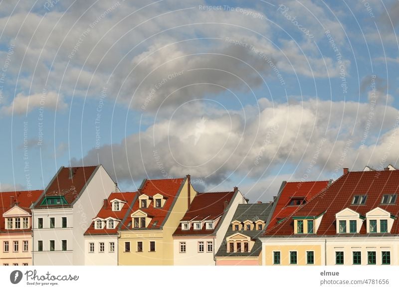 Teilansicht einer Häuserzeile mit Wohnhäusern unterschiedlicher Größe, Farbe und Bauweise sowie Schönwetterwolken / wohnen / Mietpreise Haus Hausdach Fenster