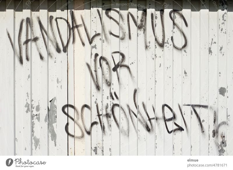 VANDALISMUS VOR SCHÖNHEIT steht in gespayten schwarzen Großbuchstaben an einer grauen Metallwand / Graffiti Vandalismus Schönheit sprayen Sachbeschädigung