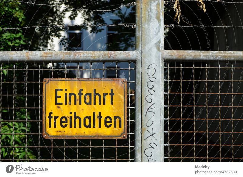 Rostiges und vergilbtes gelbes Ausfahrt freihalten Schild aus Blech mit schwarzer Schrift auf altem Drahtzaun eines Hoftor im Ostend von Frankfurt am Main in Hessen