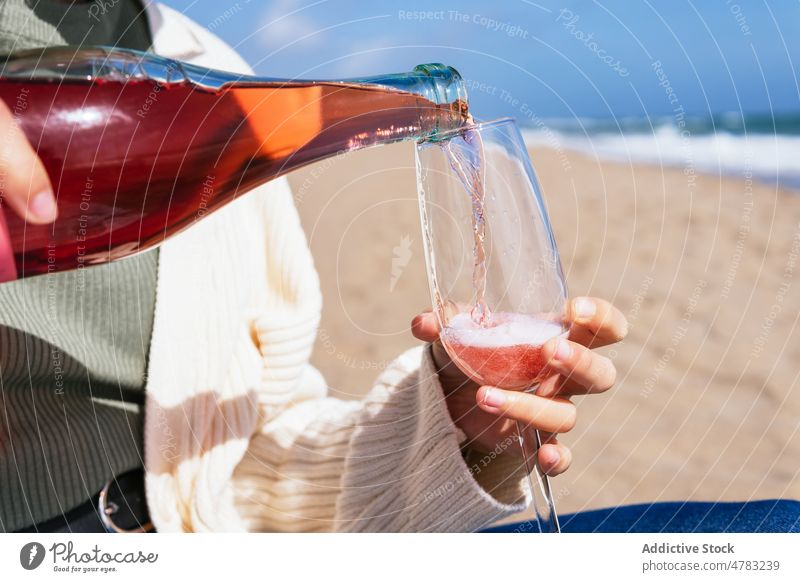 Unbekannte Frau schenkt am Strand Rosensekt ein Champagne Roséwein funkeln Wein eingießen Glas MEER Ufer Alkohol Schnaps feiern tropisch sprudeln Sand Flasche