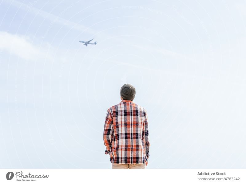 Unbekannter Mann schaut auf Flugzeug im Himmel beobachten Ebene Blauer Himmel Fluggerät bewundern nachdenken Verkehr kariertes Hemd Sonnenlicht Stil malerisch