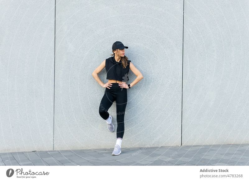Sportlerin, die in der Nähe der Mauer steht und eine Pause auf der Straße macht Großstadt Athlet Training ruhen Sportkleidung sportlich Wand fettarm Frau