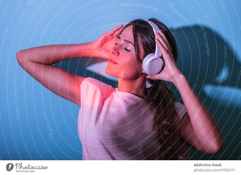 Frau hört Musik in einem Studio mit Lichtern Kopfhörer Stil rot Gesang meloman unterhalten Hobby Melodie trendy zuhören Atelier farbenfroh Klang lebhaft kreativ