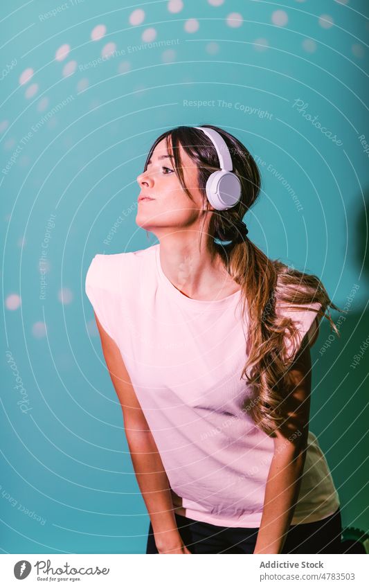 Frau hört Musik in einem Studio mit Lichtern Kopfhörer Stil Gesang meloman unterhalten Hobby Melodie trendy zuhören Atelier farbenfroh Klang lebhaft kreativ