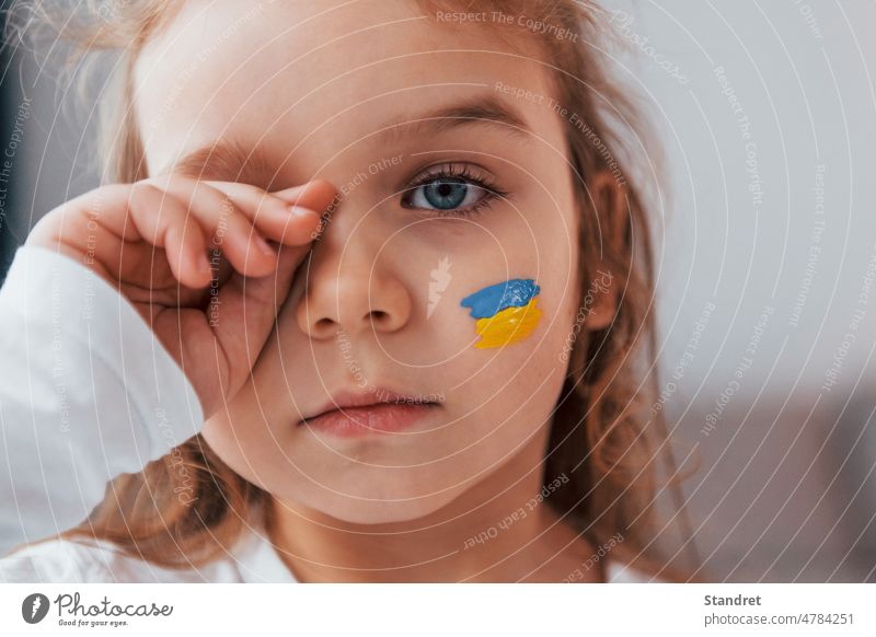 Unschuldiges Kind weint. Porträt des kleinen Mädchens mit ukrainischen Flagge Make-up auf dem Gesicht Ukraine zusammenstellen Weinen Fahne Ausdruck unschuldig