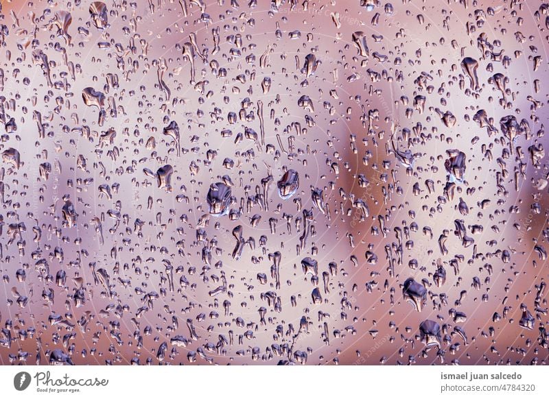 Regentropfen am Fenster an regnerischen Tagen Tropfen Wasser nass Glas grau blau durchsichtig Oberfläche Nahaufnahme abstrakt Hintergrund texturiert hell