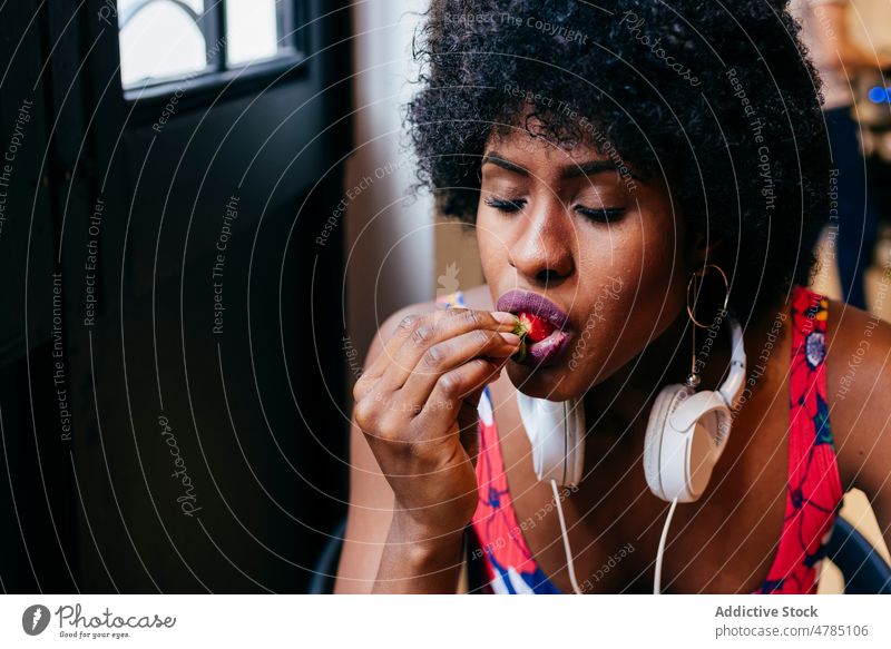 Afroamerikanische Frau isst Erdbeere Frauen Erdbeeren Biss essen genießen Frühstück Gesundheit Café Beeren jung modern Glück Vergnügen schwarz Afroamerikaner