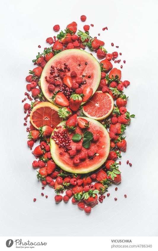 Haufen von verschiedenen roten Sommerfrüchten: Wassermelone, Grapefruit, Himbeeren, Erdbeeren und Granatapfelkerne auf weißem Hintergrund. Früchte