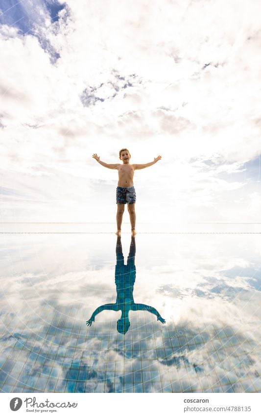 Kleines Kind am Rande eines Schwimmbeckens mit wolkigem Himmel im Hintergrund bezaubernd Bahamas Strandclub blauer Ozean Kaukasier heiter Kindheit Wolken