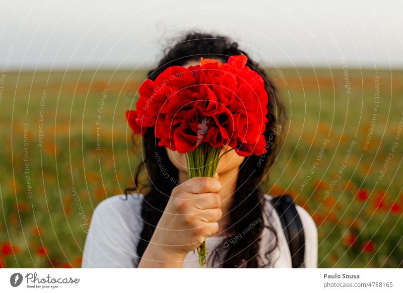 Porträt eines Mädchens, das sein Gesicht mit Mohnblumen bedeckt Frau Mohnblüte Mohnfeld Sommer Blume Blüte Außenaufnahme Natur Pflanze authentisch rot Mohnwiese