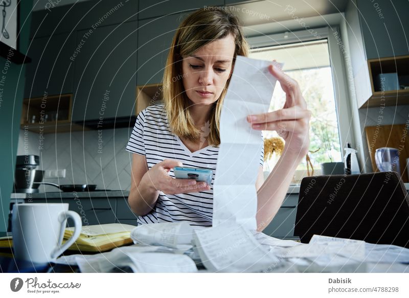 Frau beim Berechnen einer Rechnung in der Küche Steuer berechnen heimwärts Finanzen Haushaltsplan Zählen Zahlung Papier Einsparung Buchhaltung Plan