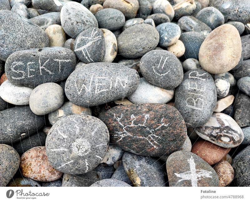 Wenn man Schätze am Strand sucht, findet man manchmal auch unerwartete kleine Botschaften. Stein Steine grau braun Schrift Buchstaben Smiley Worte