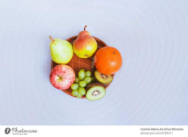Sortiment von Früchten auf einem Holzteller und weißem Hintergrund. Ackerbau Amuse-Gueule Apfel sortiert Zitrusfrüchte lecker Dessert Diät anders essen