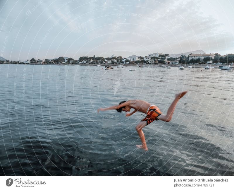 Junge, der an einem Strand in Mallorca, Balearen, Spanien, ins Meer springt springend Schwimmsport Urlaub Sommer Teenager platschen MEER jung Kind schwimmen